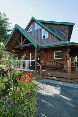 a house with a porch with a bench and flowers at Wild Coast Wilderness Resort in Port Renfrew
