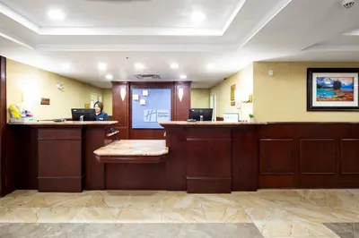 a woman sitting at a reception desk in a waiting room at Holiday Inn Express Hotel & Suites Edson by IHG in Edson