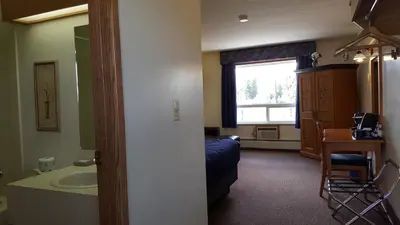 a room with a bed and a sink and a bathroom at Pines Motel in Hinton