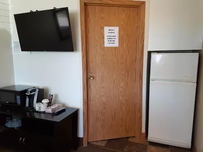 a room with a door with a television and a refrigerator at Pines Motel in Hinton