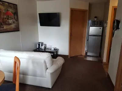 a living room with a white couch and a refrigerator at Pines Motel in Hinton