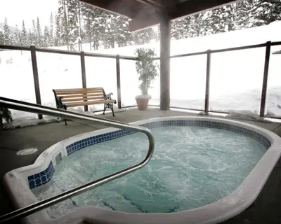 a jacuzzi tub with a bench in the snow at Cahilty Lodge in Sun Peaks