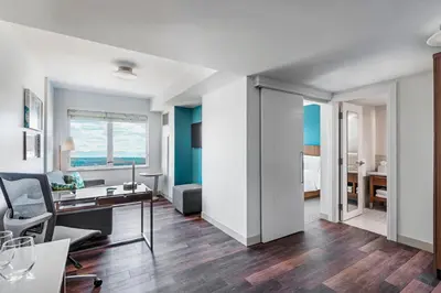 a living room with a desk and a bedroom at Element Calgary Airport in Calgary