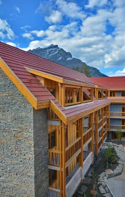 a building with a red roof with mountains in the background at Moose Hotel and Suites in Banff