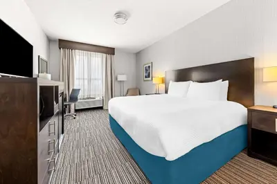 a hotel room with a bed and a flat screen tv at Best Western Plus Airdrie Gateway in Airdrie