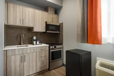 a kitchen with wooden cabinets and a black refrigerator at Ramada by Wyndham West Edmonton Hotel & Suites in Edmonton