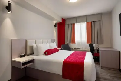 a hotel room with a large bed with a red blanket at Ramada by Wyndham West Edmonton Hotel & Suites in Edmonton