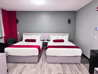 two beds in a room with red and white at Ramada by Wyndham West Edmonton Hotel & Suites in Edmonton