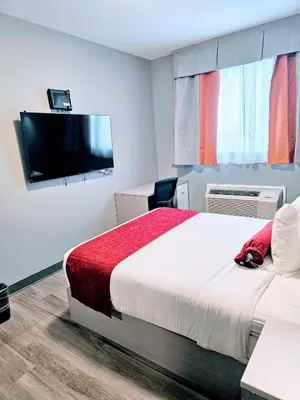 a hotel room with a bed and a flat screen tv at Ramada by Wyndham West Edmonton Hotel & Suites in Edmonton