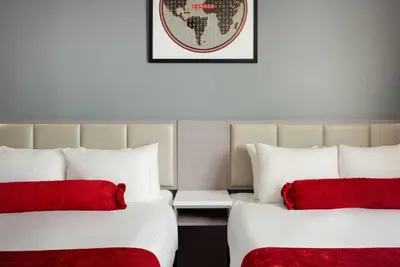 two beds with red pillows in a hotel room at Ramada by Wyndham West Edmonton Hotel & Suites in Edmonton