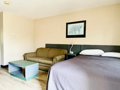 a bedroom with a bed and a couch at Plains Motor Inn in Stettler