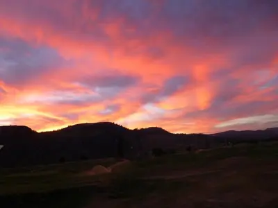 a sunset over a field with a mountain at Overlander B&B in Kamloops