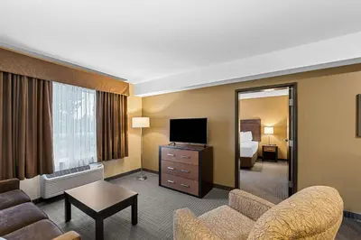 a living room with a couch and a television in a hotel room at Best Western Plus Lacombe Inn and Suites in Lacombe