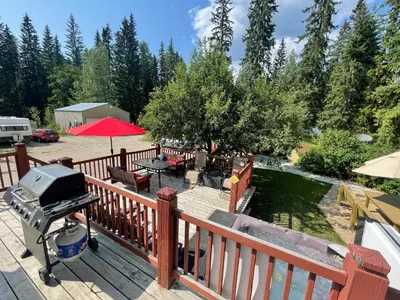 a grill on a wooden deck with a backyard at Blaeberry Valley Vacation Rentals in Golden