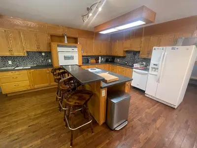 a kitchen with wooden cabinets and a white refrigerator at Blaeberry Valley Vacation Rentals in Golden