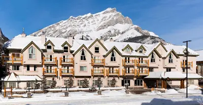 a large building with a snow covered mountain in the background at The Rundlestone Lodge in Banff