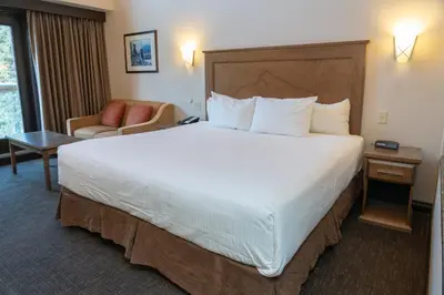 a hotel room with a large bed and a chair at The Rundlestone Lodge in Banff