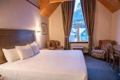 a bedroom with a large white bed and a window at The Rundlestone Lodge in Banff