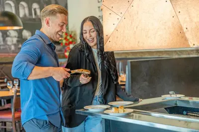 a man and a woman preparing food in a kitchen at Acclaim Hotel by CLIQUE in Calgary