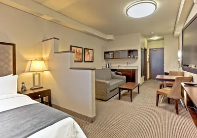 a hotel room with a bed and a living room at Acclaim Hotel by CLIQUE in Calgary