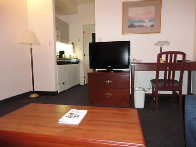 a living room with a tv and a table at Rosedale on Robson Suite Hotel in Vancouver