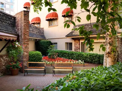 two benches sitting in front of a building with flowers at Royal Scot Hotel & Suites in Victoria