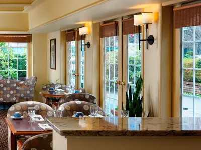 a dining room with tables and chairs and windows at Royal Scot Hotel & Suites in Victoria
