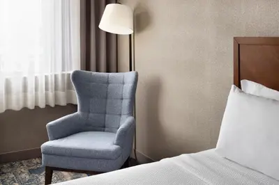 a bedroom with a chair and a bed and a lamp at Four Points by Sheraton Edmonton South in Edmonton