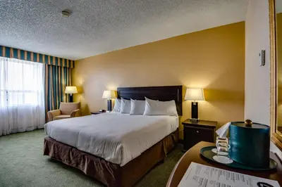a hotel room with a large bed and a chair at Sawridge Inn and Conference Centre Edmonton South in Edmonton