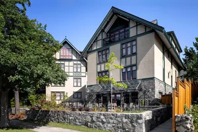 a large white building with a stone wall at Abigail's Hotel in Victoria