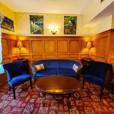 a living room with blue chairs and a table at James Bay Inn Hotel, Suites & Cottage in Victoria
