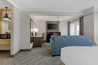 a hotel room with a blue couch and a desk at Best Western Cedar Park Inn in Edmonton