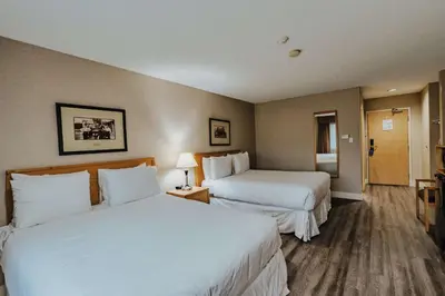 a hotel room with two beds with white sheets at SureStay Plus by Best Western Coquitlam in Coquitlam