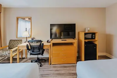 a hotel room with a desk with a computer and a television at SureStay Plus by Best Western Coquitlam in Coquitlam