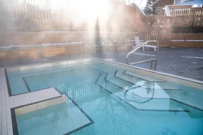 a swimming pool with a bench and a chair in it at Banff Rocky Mountain Resort in Banff