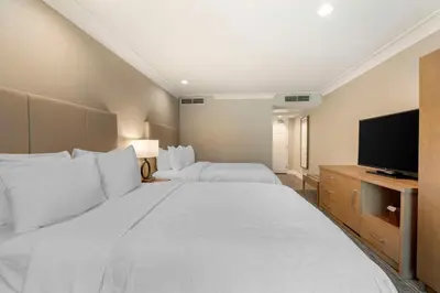 a hotel room with two beds and a flat screen tv at Best Western Plus Kelowna Hotel & Suites in Kelowna