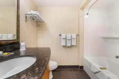 a bathroom with a tub and a toilet and a sink at Best Western Plus Kelowna Hotel & Suites in Kelowna