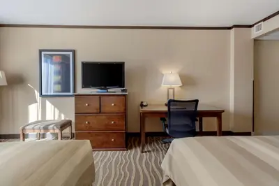 a hotel room with two beds and a desk and a television at Best Western Premier Denham Inn & Suites in Leduc