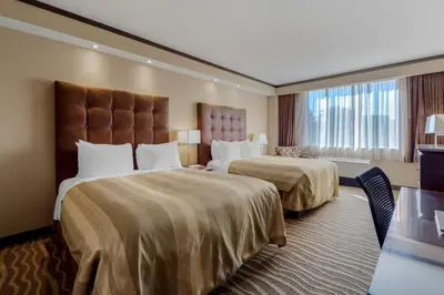 a hotel room with two beds and a window at Best Western Premier Denham Inn & Suites in Leduc