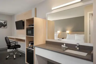 a hotel room with a bed and a mirror at Days Inn by Wyndham Kelowna in Kelowna