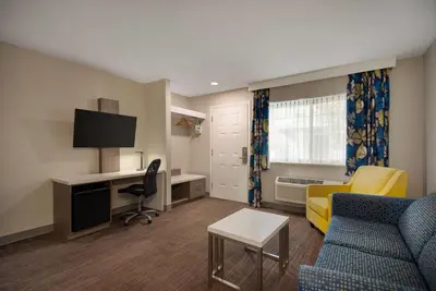 a living room with a couch and a desk at Days Inn by Wyndham Kelowna in Kelowna