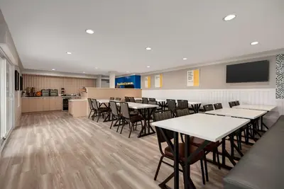 a dining room with tables and chairs and a kitchen at Days Inn by Wyndham Kelowna in Kelowna