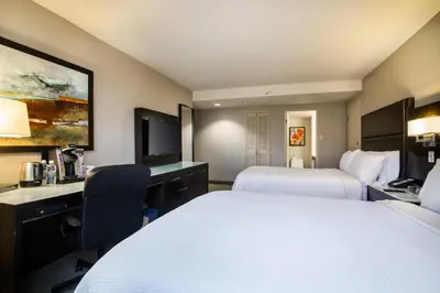 a hotel room with two beds and a desk at Holiday Inn Vancouver-Centre Broadway by IHG in Vancouver