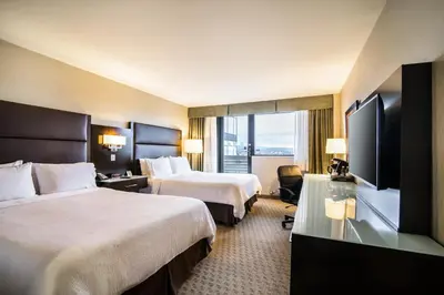a hotel room with two beds and a flat screen tv at Holiday Inn Vancouver-Centre Broadway by IHG in Vancouver