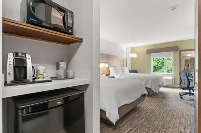 a hotel room with a bed and a tv on a shelf at Holiday Inn Express and Suites Surrey by IHG in Surrey