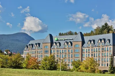 a large building with a mountain in the background at Holiday Inn & Suites North Vancouver by IHG in North Vancouver
