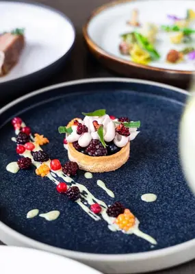 a dessert on a blue plate with fruit on it at The Magnolia Hotel & Spa in Victoria