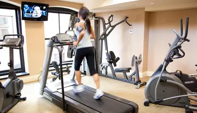 a woman walking on a treadmill in a gym at The Magnolia Hotel & Spa in Victoria
