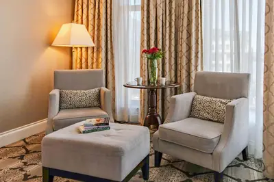 a living room with two chairs and a ottoman at The Magnolia Hotel & Spa in Victoria