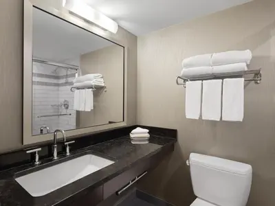 a bathroom with a sink and a mirror and a toilet at Holiday Inn Calgary Airport by IHG in Calgary